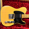 Vintage Fender Telecaster electric guitar in aged yellow finish with black pickguard on red velvet guitar case interior