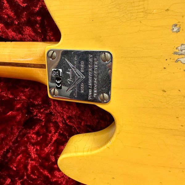 Close-up of Fender Custom Shop 70th Anniversary Telecaster neck plate on yellow relic finish guitar body with red plush case lining background