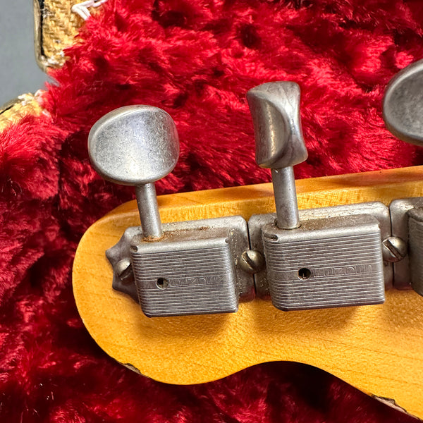 Close-up of vintage guitar tuning pegs and headstock on red plush case interior