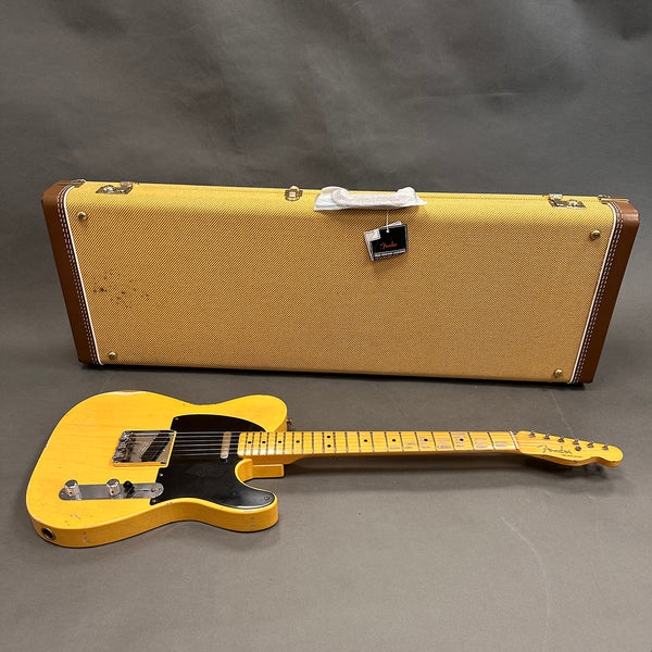 Vintage Fender Telecaster electric guitar with black pickguard and maple neck, displayed with tweed Fender hard case on gray background