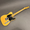 Vintage Fender Telecaster electric guitar with worn blonde finish and black pickguard on gray background