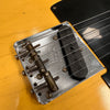Close-up of vintage Fender Telecaster bridge and single-coil pickup on butterscotch blonde electric guitar body with metal bridge plate and aged saddles