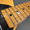 Close-up of vintage electric guitar maple neck with worn fretboard and black dot inlays, showing steel strings and black pickguard.