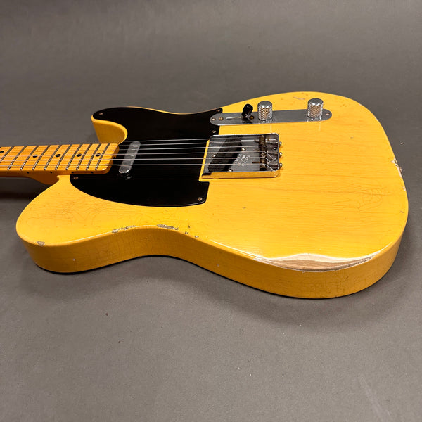Vintage yellow electric guitar with black pickguard and chrome hardware on gray background