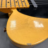 Close-up of vintage yellow electric guitar body with visible wear, cracked finish, and black pickguard next to fretboard with metal strings and inlay dots.