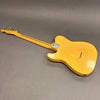 Vintage worn yellow electric guitar with maple neck and six tuning pegs lying face down on gray surface