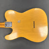Back view of vintage yellow electric guitar body with string ferrules and neck plate on gray background