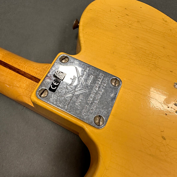 Close-up of Fender 70th Anniversary 1950-2020 Telecaster metal neck plate on vintage yellow guitar body showing wood grain and wear details