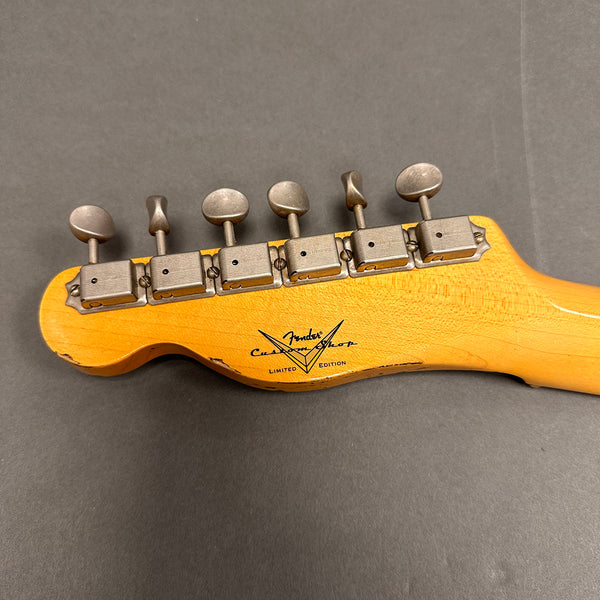 Close-up of vintage Fender Custom Shop Limited Edition guitar headstock with six tuning pegs and worn finish on a gray background