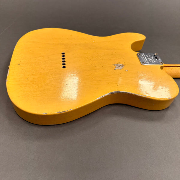 Back of vintage yellow electric guitar body with chrome neck plate and string ferrules on gray background