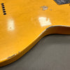 Close-up of vintage yellow electric guitar body showing worn finish and paint chips on the edge, highlighting relic details and aging effect