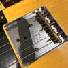 Close-up of Fender guitar vintage bridge and single-coil pickup with strings and worn yellow finish
