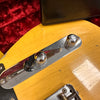 Close-up of vintage electric guitar control plate with chrome knobs and yellow aged finish, showing wear and crackle in the lacquer.