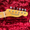 Close-up of Fender Telecaster guitar headstock with six tuning pegs on red plush case lining