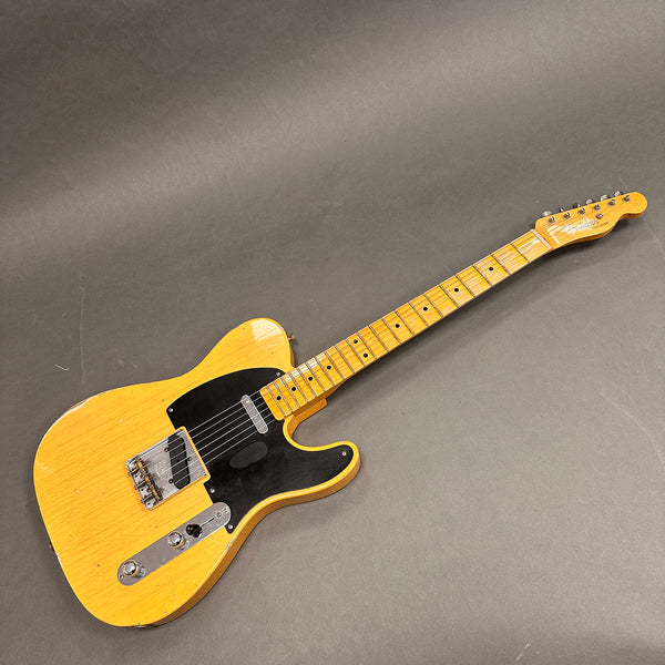 Vintage Fender Telecaster electric guitar with butterscotch blonde finish and black pickguard on gray background