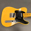 Vintage yellow electric guitar with black pickguard and maple neck showing wear and cracking finish detail