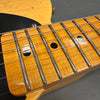 Close-up image of a vintage electric guitar maple neck with worn finish, chrome frets, and black dot inlays on a light amber fretboard.