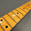 Close-up of maple guitar neck and fretboard with metal frets and black dot inlays on gray background