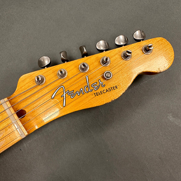 Close-up of vintage Fender Telecaster guitar headstock with tuning pegs and strings on gray background