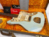 Fender Jazzmaster Relic electric guitar in light blue finish with worn edges, two white P-90 style pickups, gold anodized pickguard, volume and tone knobs, and tortoiseshell bridge cover inside an orange plush-lined hard case with Fender Custom Shop certificate and manuals visible