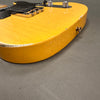 Close-up of worn yellow electric guitar body with chrome knobs and bridge on gray background