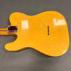 Vintage yellow electric guitar body with visible wear and finish checking on gray background showing back side with string ferrules and neck plate