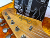 Close-up of Fender Jazzmaster electric guitar headstock with tuning pegs and logo in vintage-style case with orange plush lining and guitar schematic background