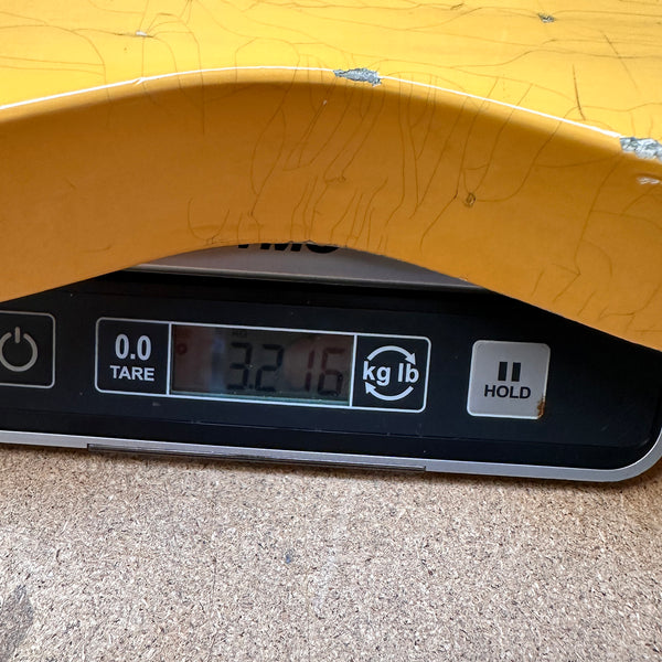 Close-up of yellow guitar body showing wear and damage placed on digital scale weighing 3.216 pounds at Coffee House Guitars