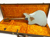 Vintage worn light blue electric guitar with visible wood patches and scratches, resting inside an open brown guitar case lined with bright orange plush interior.