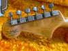 Close-up of Fender Custom Shop Limited Edition guitar headstock with vintage tuning pegs on plush yellow-orange case lining