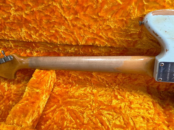 Vintage worn maple guitar neck with faded finish on orange plush guitar case lining