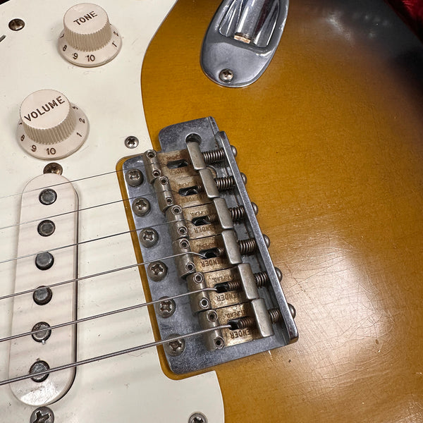 Close-up of vintage electric guitar bridge and pickups with tone and volume control knobs on sunburst finish guitar body