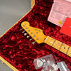 Close-up of Fender Stratocaster maple neck and headstock inside red plush-lined guitar case with paperwork and guitar picks in plastic container