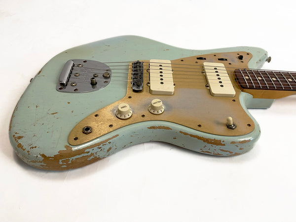 Vintage worn light blue electric guitar with two white pickups, cream tone and volume knobs, and a gold pickguard on white background