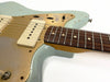 Close-up of vintage electric guitar with light blue distressed finish, gold pickguard, cream single-coil pickups, and rosewood fretboard with dot inlays