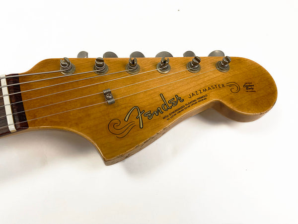 Close-up of Fender Jazzmaster guitar headstock with natural wood finish and chrome tuning pegs on white background