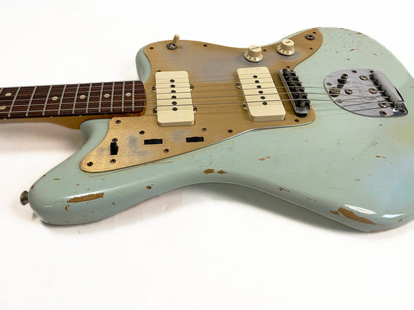 Vintage electric guitar with worn light blue finish, gold pickguard, dual cream single-coil pickups, and rosewood fretboard on white background