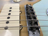 Close-up of vintage electric guitar bridge and single-coil pickup with string springs and aged hardware on natural wood finish body