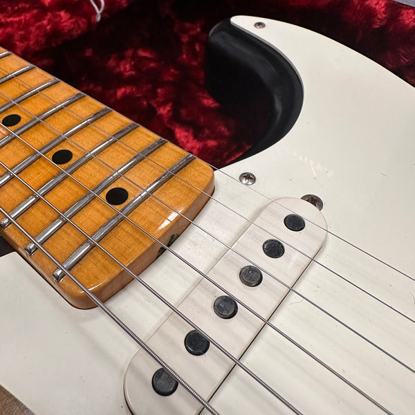 Close-up of electric guitar maple fretboard and single-coil pickups on white body with red velvet background case interior