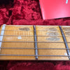 Close-up of maple guitar fretboard with metal frets and steel strings on red velvet background