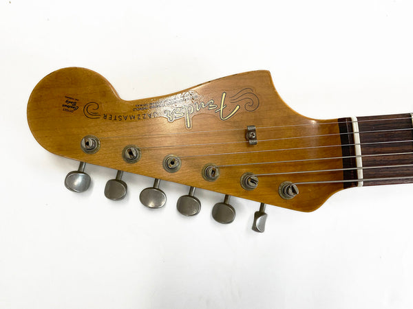 Close-up of vintage Fender Jazzmaster guitar headstock with six tuning pegs and strings on white background