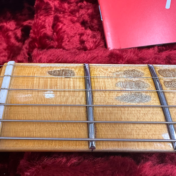 Close-up of maple guitar fretboard with metal frets and steel strings on red velvet background
