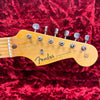 Close-up of Fender Stratocaster guitar headstock with vintage tuners on red plush background