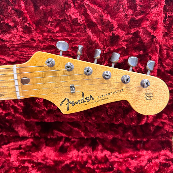 Close-up of Fender Stratocaster guitar headstock with vintage tuners on red plush background