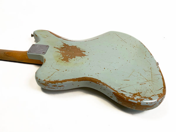 Back of vintage Fender electric guitar body with worn light blue paint and exposed wood on white background