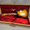 Fender Custom Shop electric guitar in sunburst finish inside open vintage tweed case with red plush interior showing back of guitar body and neck