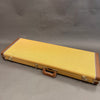 Vintage tan tweed rectangular guitar case with brown leather handle and corner protectors, gold latches, on gray background