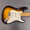 Sunburst electric guitar with maple neck, three single-coil pickups, white pickguard, and control knobs on gray background