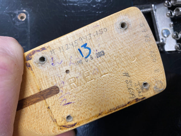 Close-up of vintage Fender guitar neck heel showing serial number, hand-written markings, and April 8, 2013 date stamp for authenticity verification