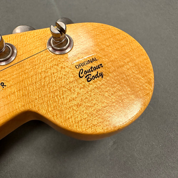 Close-up of guitar headstock with vintage tuning pegs and "Original Contour Body" decal on natural wood finish